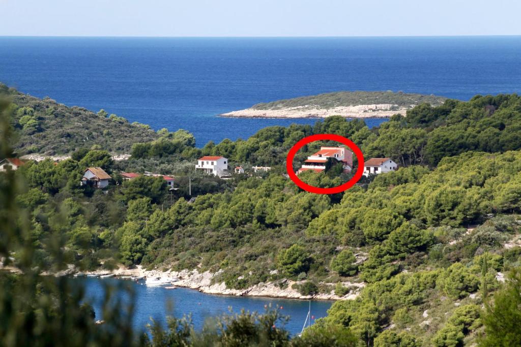 a house on a hill next to a body of water at Studio Maslinica 5180a in Maslinica