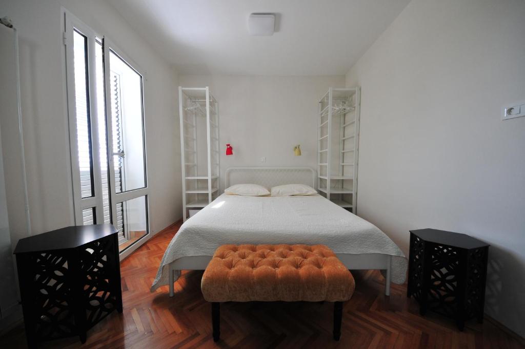 a bedroom with a bed with a ottoman and two windows at Double Room Banjol 5077a in Rab