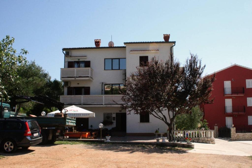 ein großes weißes Gebäude mit einem Baum davor in der Unterkunft Double Room Palit 5044b in Rab