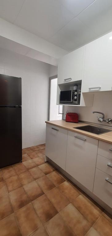 La cuisine est équipée de placards blancs et d'un réfrigérateur noir. dans l'établissement La Chirrichana 2, à Bicorp
