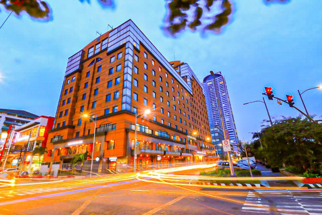 马尼拉Bayview Park Hotel Manila的夜晚城市街道上的一栋大楼