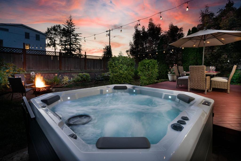 een hot tub in de achtertuin met een tafel en een parasol bij Entire house with Four Bedrooms, Hot Tub, BBQ, Private Backyard, FREE WiFi and Parking, near Seattle, EV in Lynnwood