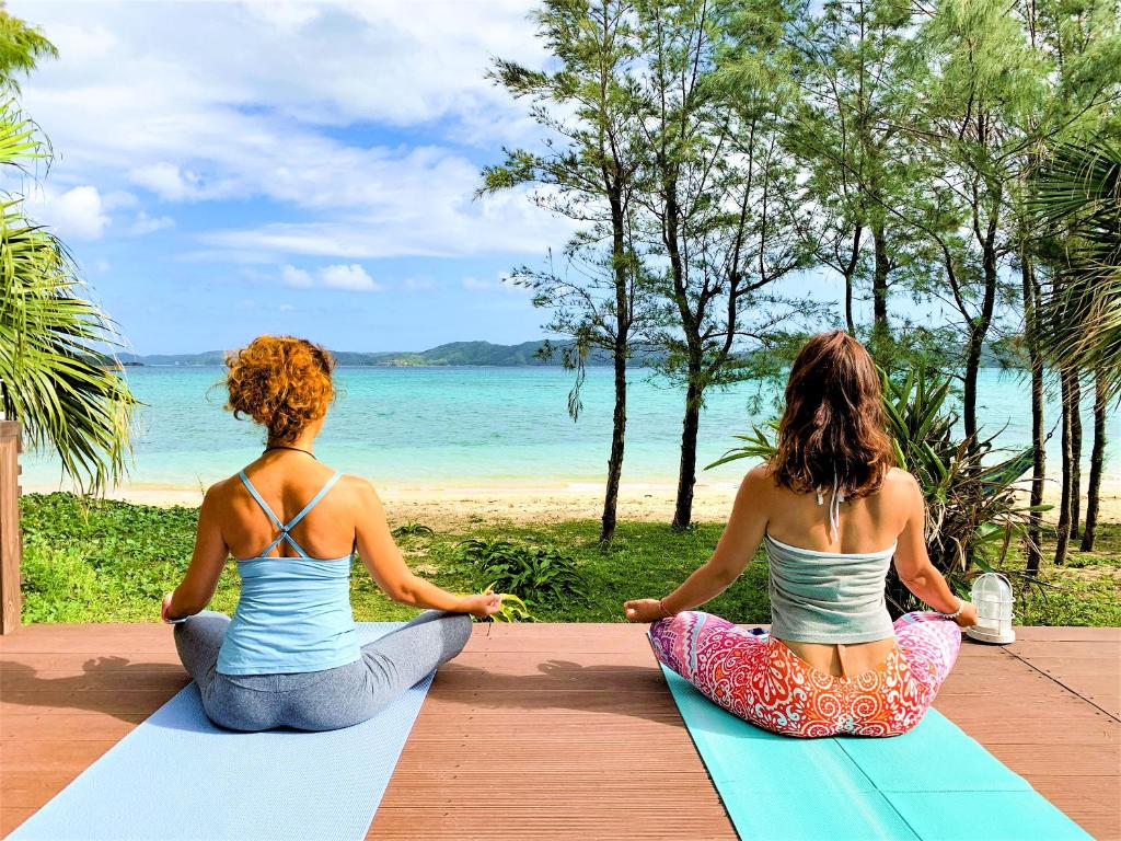 two women sitting in a yoga pose on the beach at Le Grand Bleu in Amami