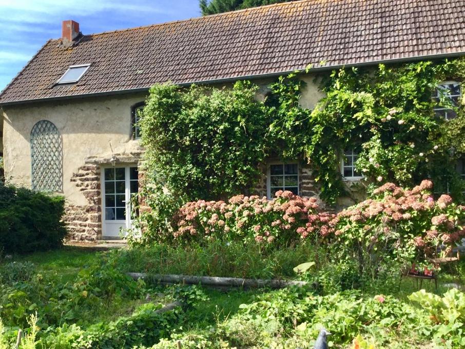 une maison avec du lierre poussant sur le côté dans l'établissement GITE EQUESTRE DE LA LANDE, à Bréhal