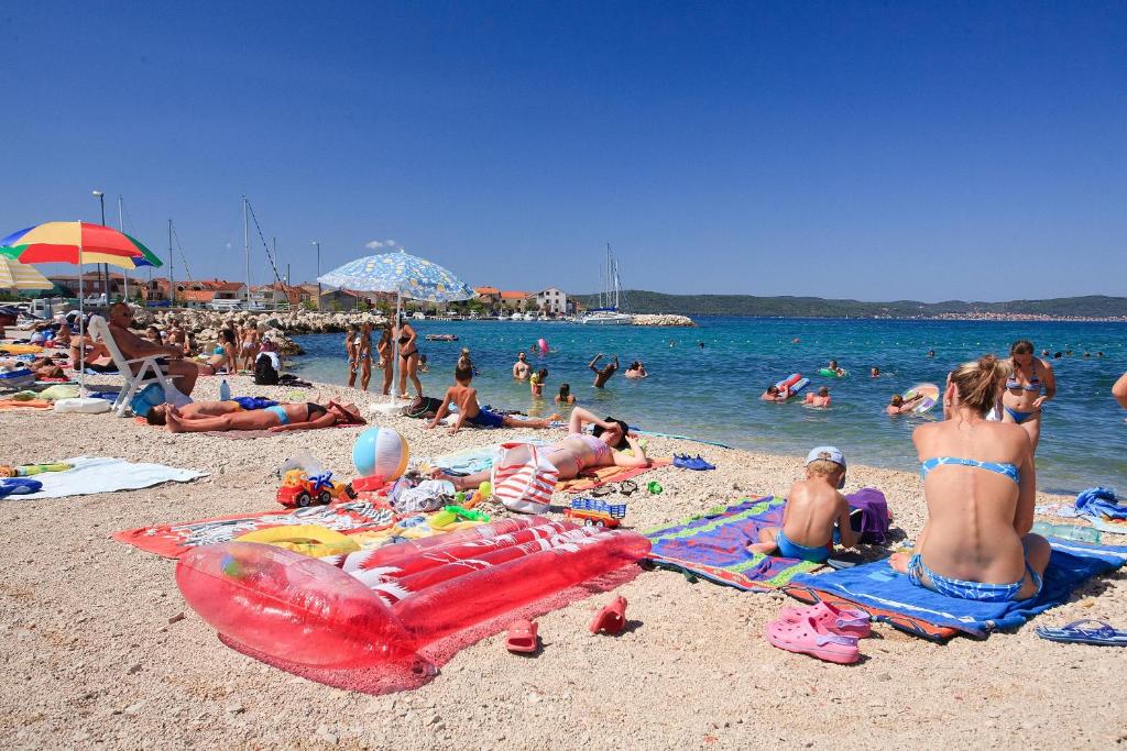 a group of people laying on a beach at Apartments with a parking space Bibinje, Zadar - 18275 in Bibinje