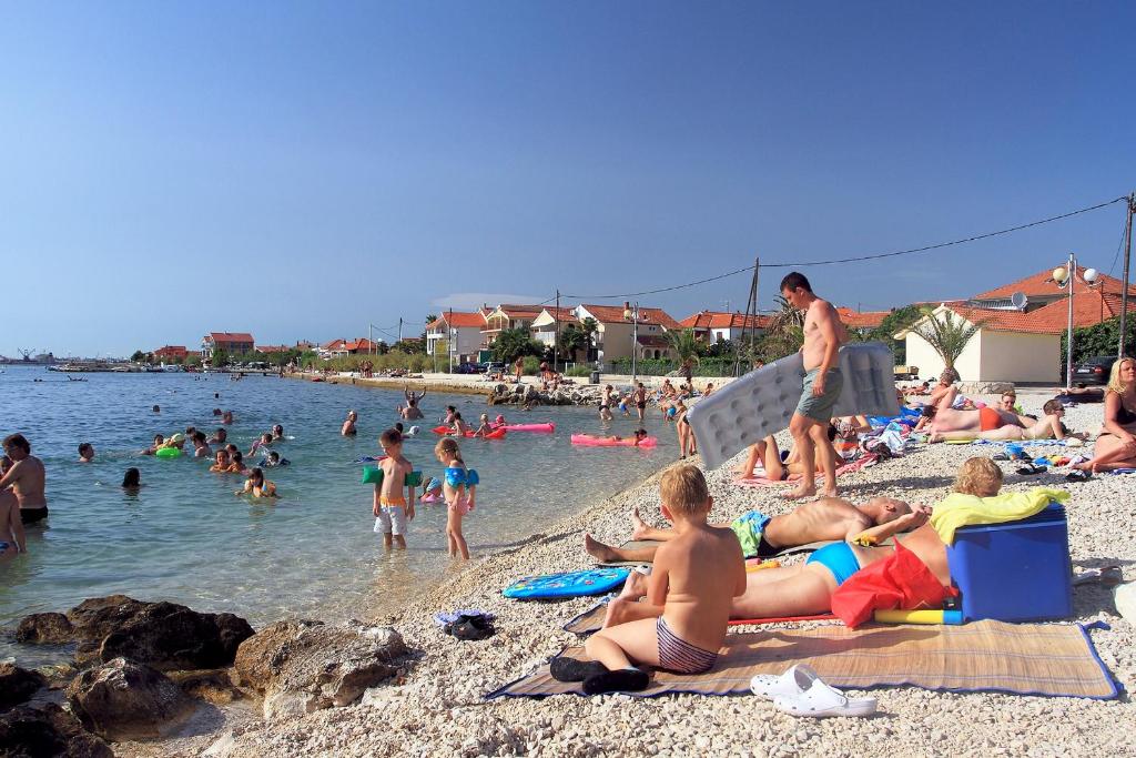 a group of people on the beach at the water at Apartments with a parking space Bibinje, Zadar - 18275 in Bibinje