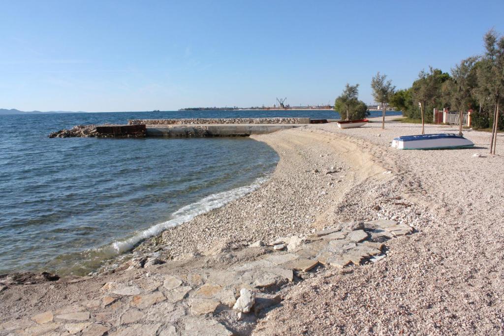 a rocky beach with a pier in the water at Apartments with a parking space Bibinje, Zadar - 18110 in Bibinje