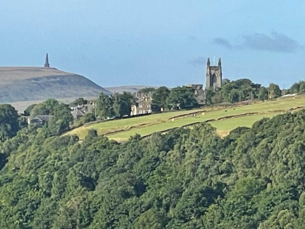 a village on a hill with a church and trees at Inviting 4 Berth caravan in Hebden Bridge in Halifax