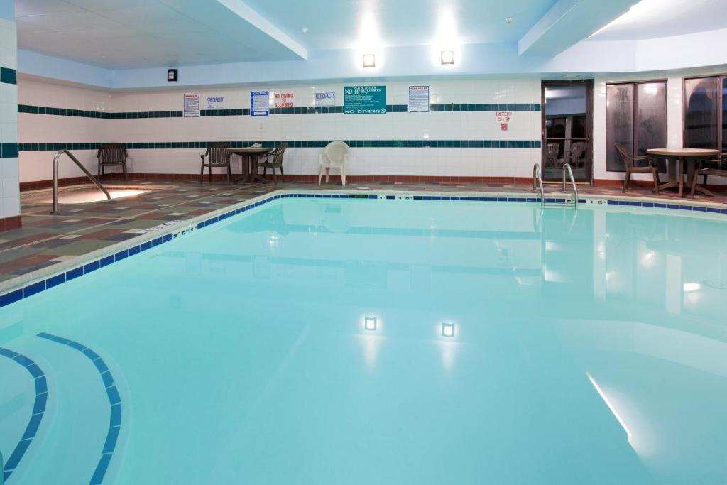 a large swimming pool in a room with tables and chairs at Holiday Inn Express & Suites Colorado Springs North, an IHG Hotel in Colorado Springs