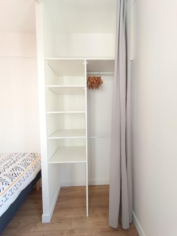 a closet with white shelves and a bed in a room at L&#39;Atelier d&#39;Oscar in Le Havre