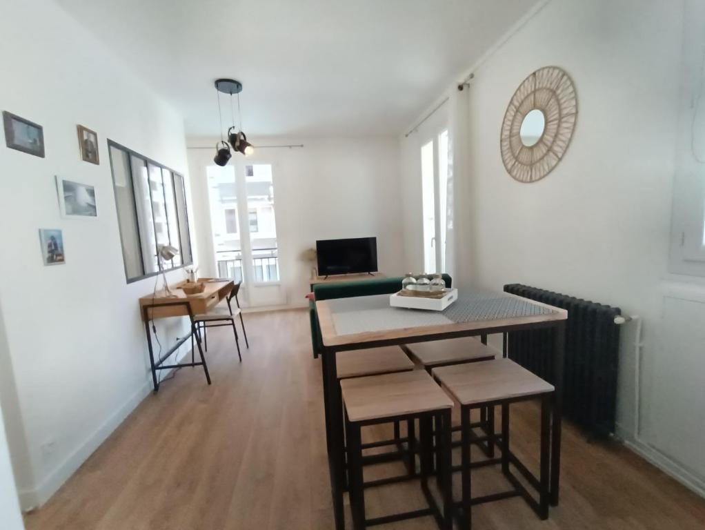 a living room with a table and chairs and a television at L&#39;Atelier d&#39;Oscar in Le Havre