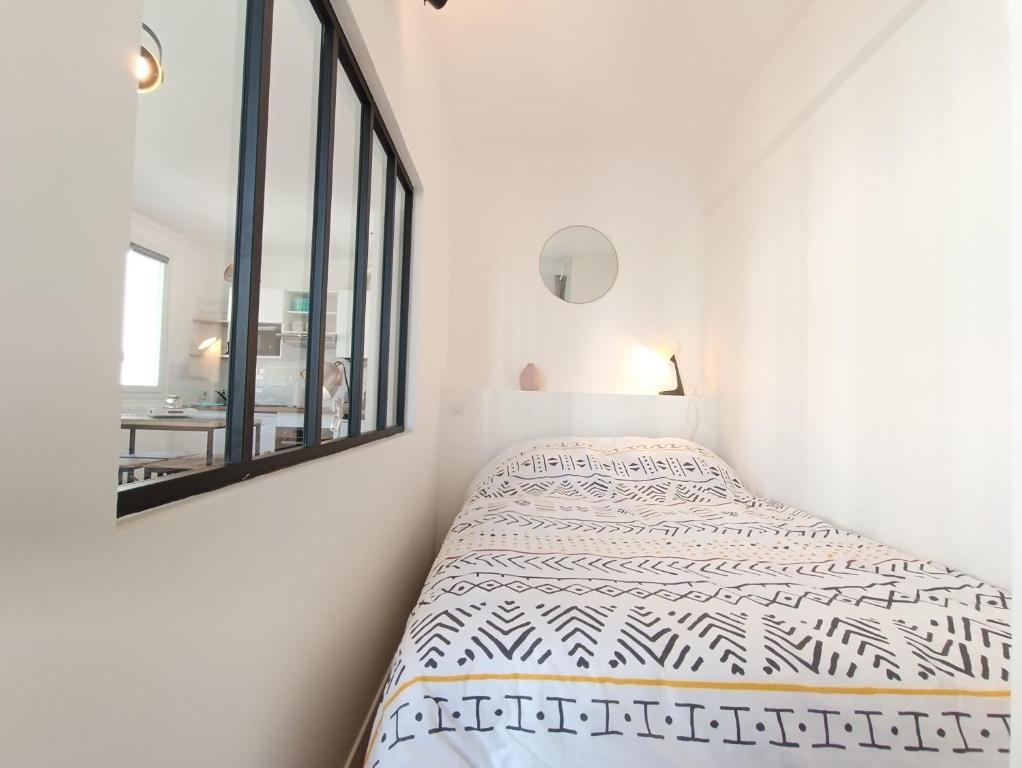 a white bedroom with a bed and a mirror at L&#39;Atelier d&#39;Oscar in Le Havre