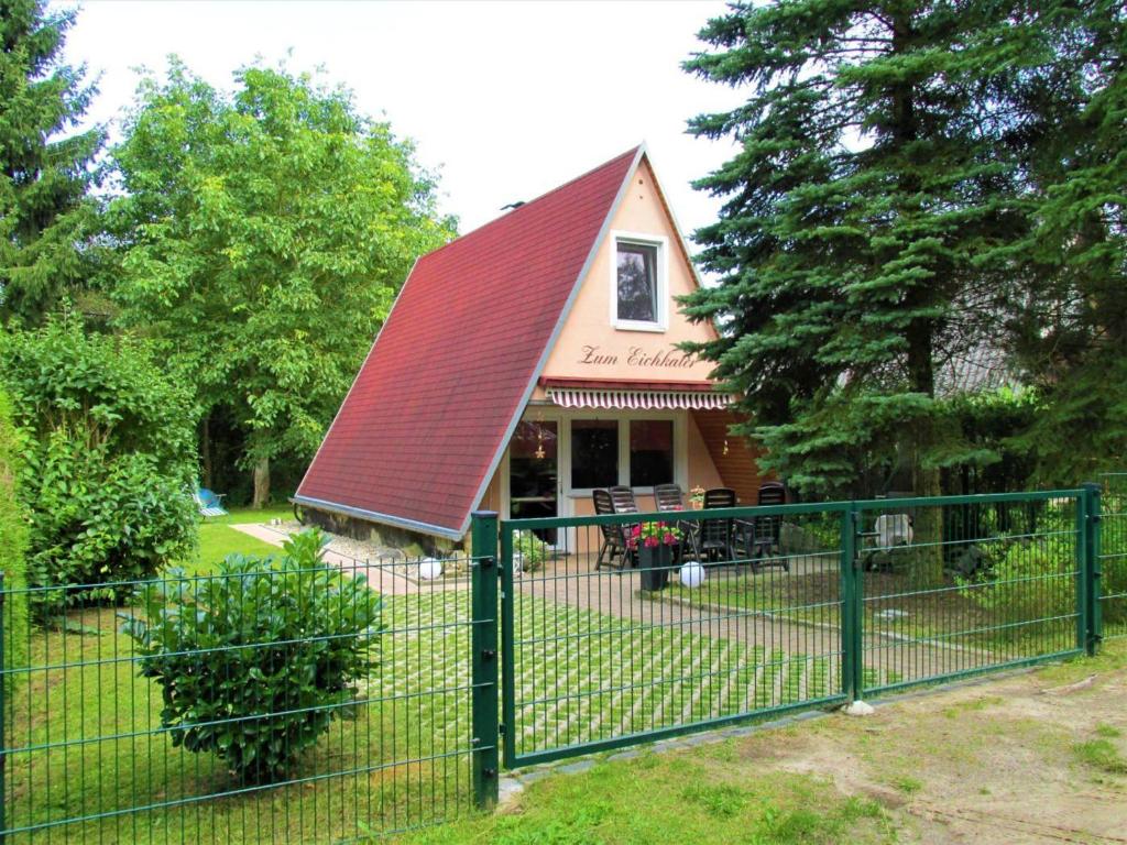 a fence in front of a house with a red roof at Ferienhaus-Zum-Eichkater-am-Duemmer-See 