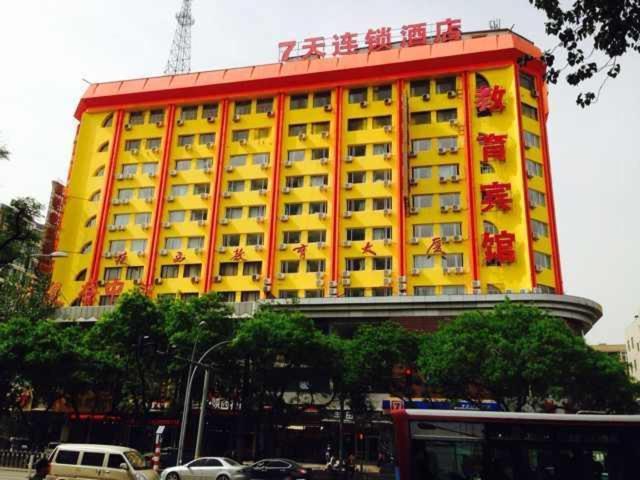 a yellow and red building with cars in front of it at 7Days Inn Xi'an North Street Subway Station Lianhu Park in Xi'an