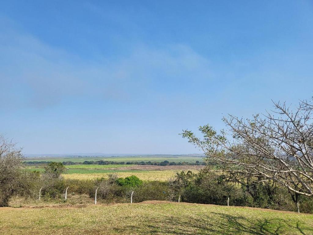 a field of grass with a fence and trees at Entsabeni Cottage in Big Bend