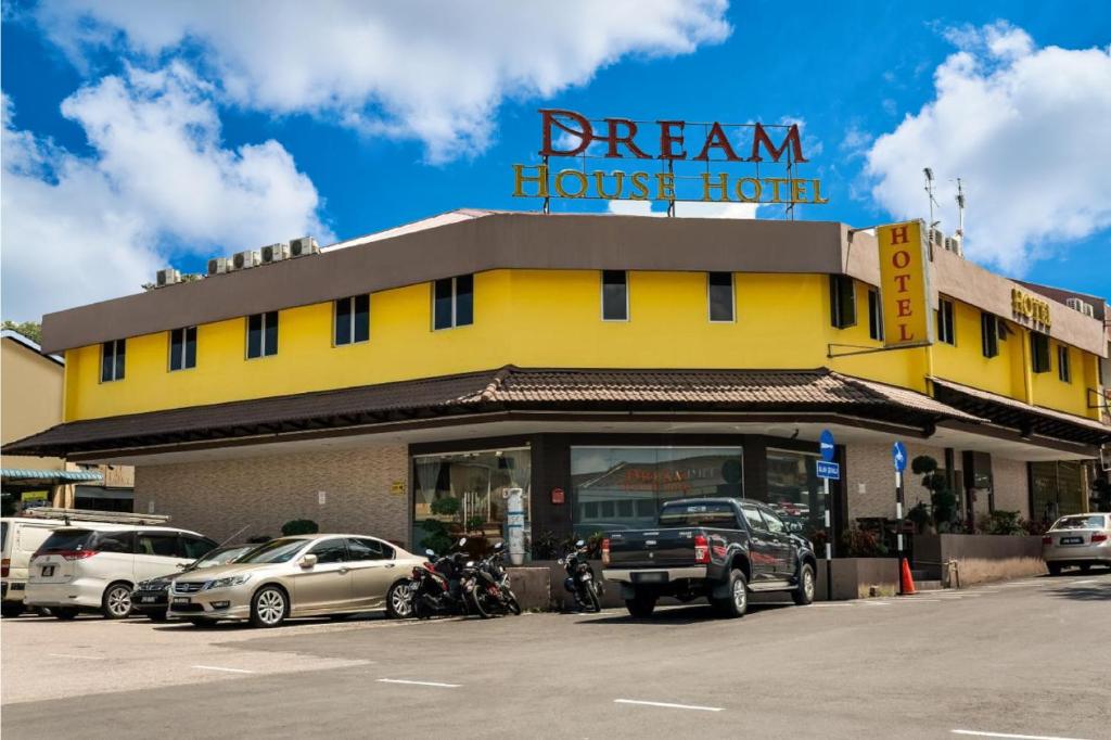 a yellow building with cars parked in front of it at Dream House Hotel in Skudai