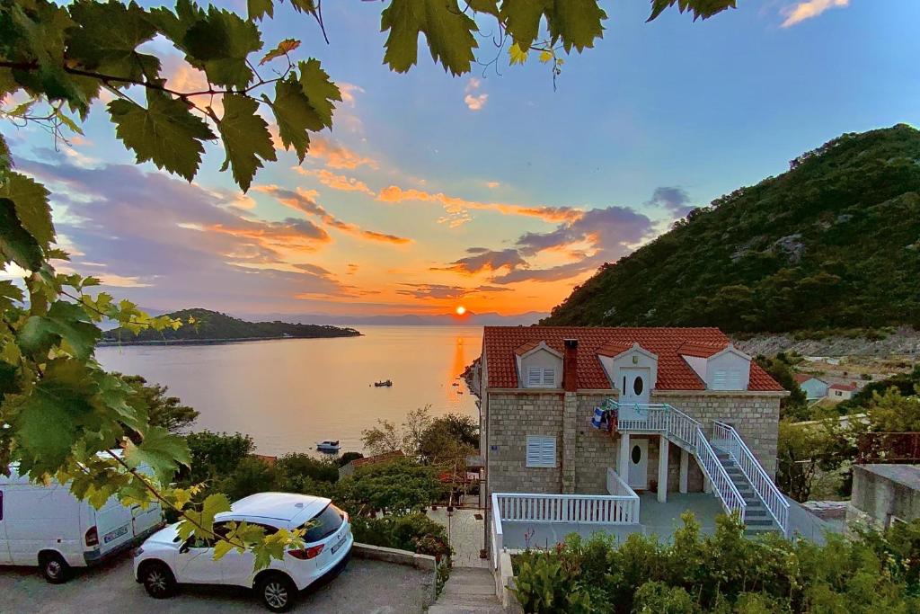 a house with a car parked in front of a sunset at Apartments with a parking space Sobra, Mljet - 4926 in Babino Polje