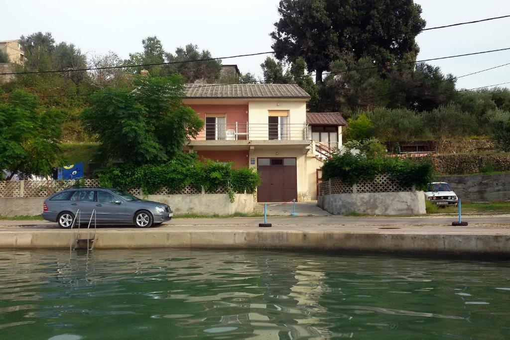 a car parked in front of a house next to a body of water at Apartments by the sea Supetarska Draga - Donja, Rab - 5042 in Supetarska Draga
