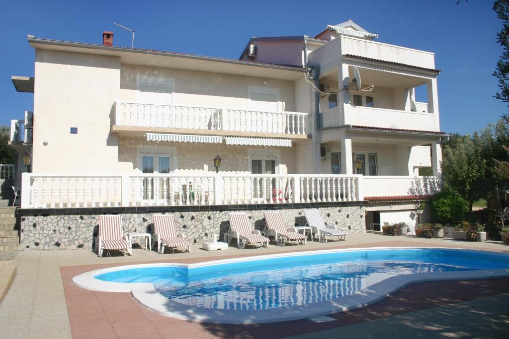 Villa con piscina frente a un edificio en Seaside apartments with a swimming pool Barbat, Rab - 4951, en Rab