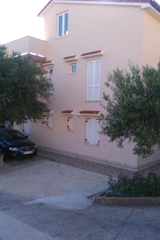 a white building with a car parked in front of it at Apartments with parking space Banjol, Rab - 4956 in Rab