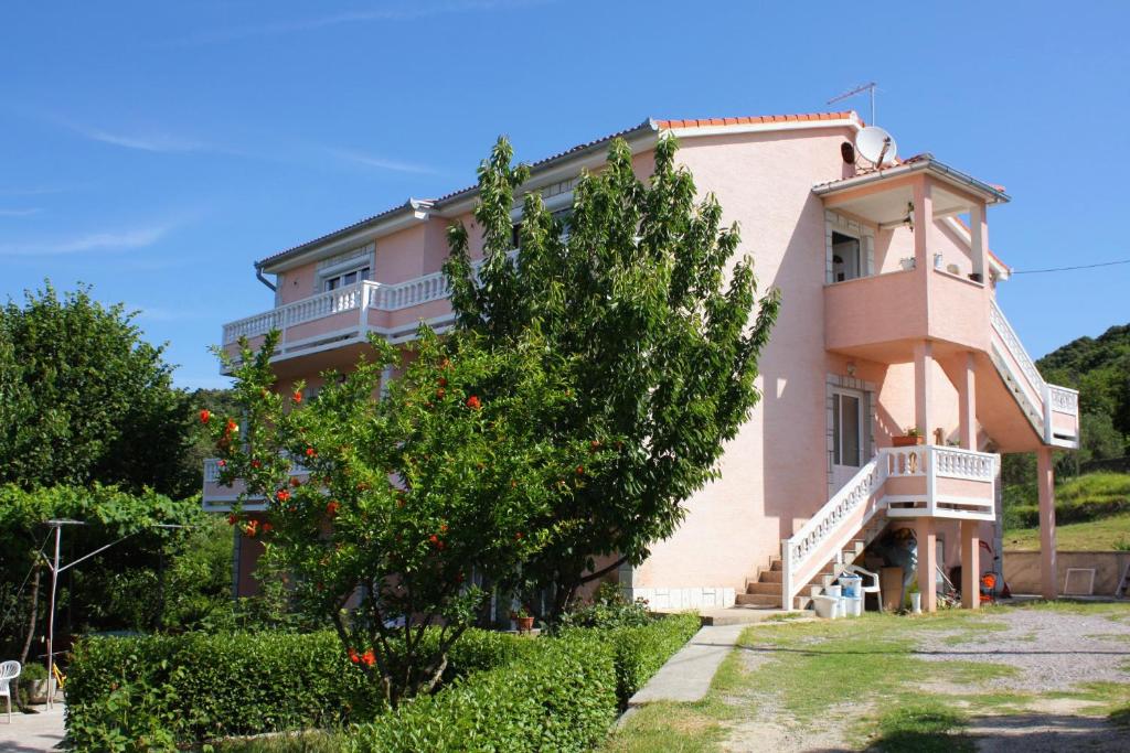 a large pink house with a tree in front of it at Apartments with a parking space Kampor, Rab - 5029 in Kampor