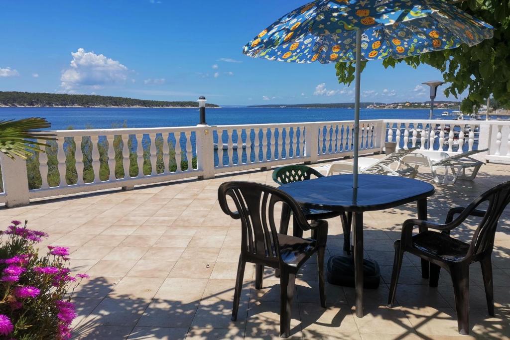 a table with chairs and an umbrella on a patio at Apartments by the sea Barbat, Rab - 4975 in Rab