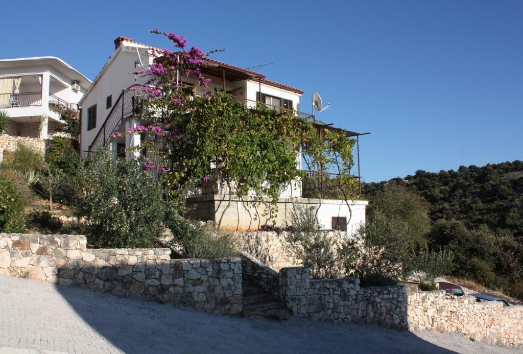 a building with a retaining wall and purple flowers at Apartments by the sea Sevid, Trogir - 5221 in Sevid
