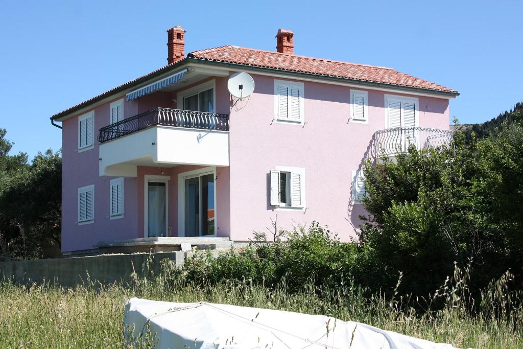 una casa rosa al lado de una colina en Apartments and rooms by the sea Barbat, Rab - 5068, en Rab