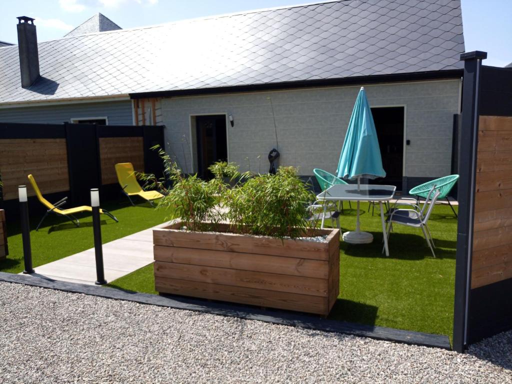 un patio con una mesa y una sombrilla azul en La suite détendue, en Saint-Blimont