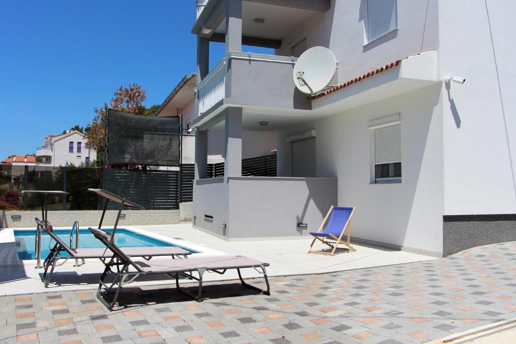 a house with two chairs and a swimming pool at Family friendly apartments with a swimming pool Tisno, Murter - 5073 in Tisno