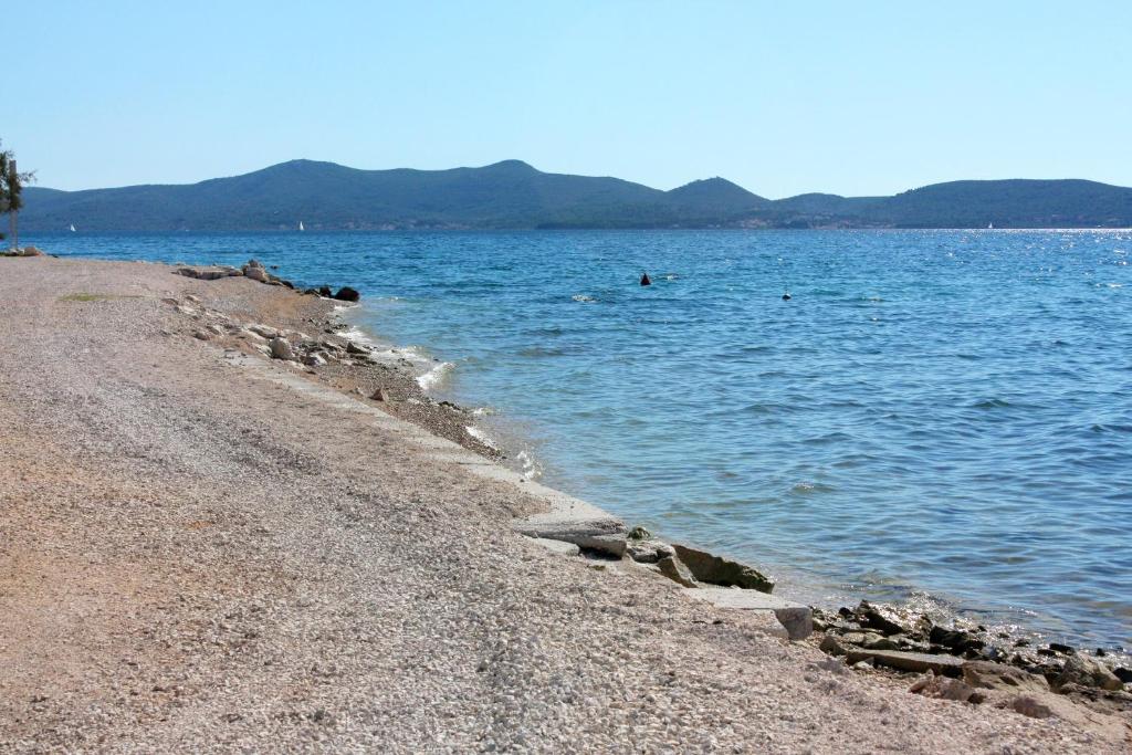 una playa con gente nadando en el agua en Apartments by the sea Bibinje, Zadar - 5786, en Bibinje