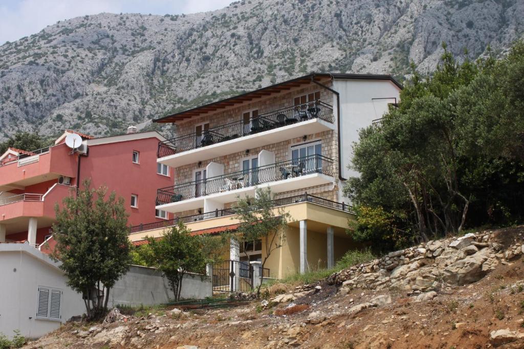 a building on a hill with mountains in the background at Apartments with a parking space Zivogosce - Porat, Makarska - 6700 in Igrane