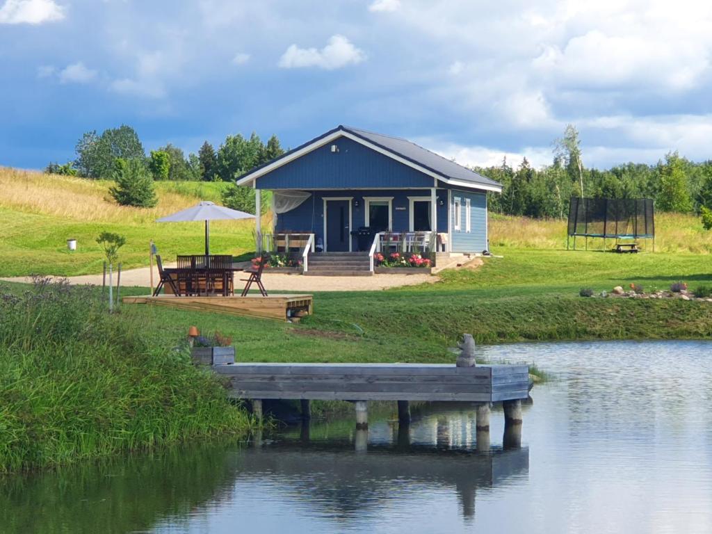 a blue house with a dock in front of a lake at Kalda Holiday Home in Otepää