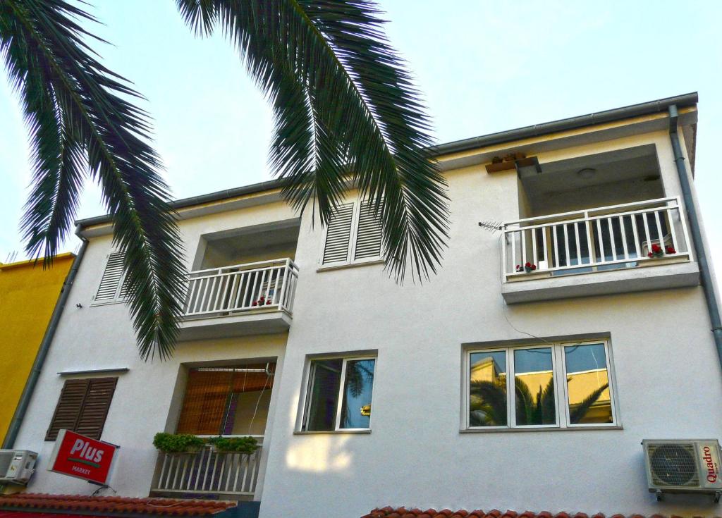 a white building with two balconies and a palm tree at Apartments by the sea Drvenik Donja vala, Makarska - 6756 in Drvenik