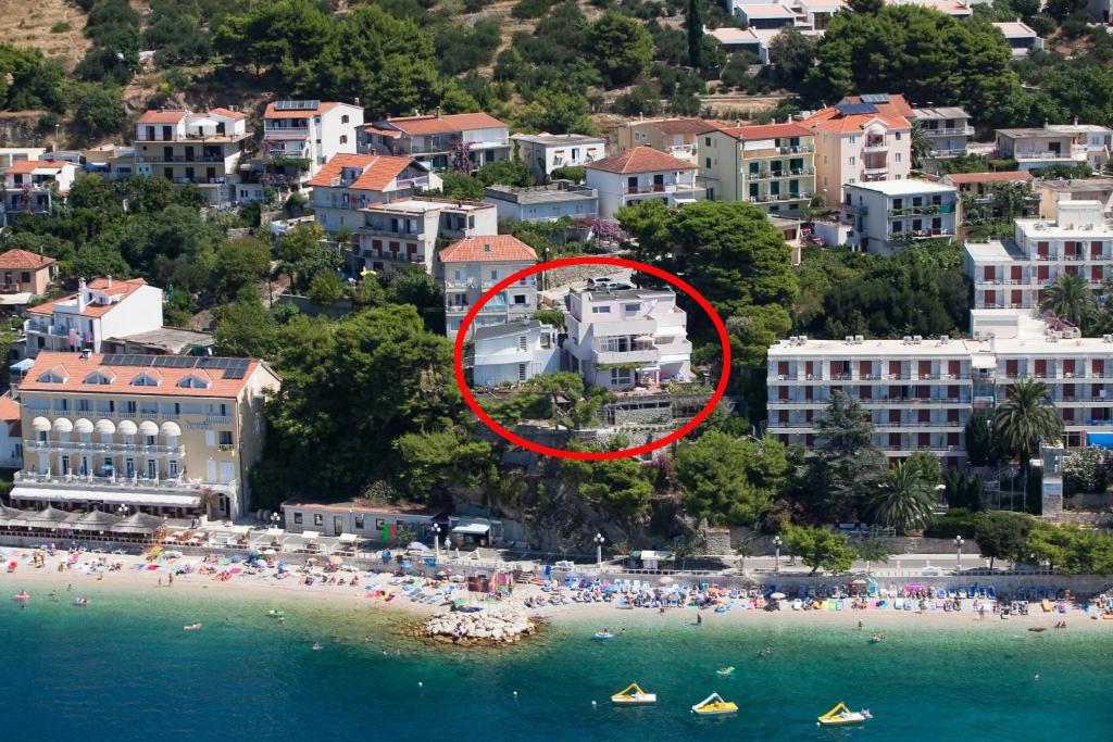 un groupe de personnes sur une plage avec une maison dans l'établissement Apartments by the sea Podgora, Makarska - 6805, à Podgora