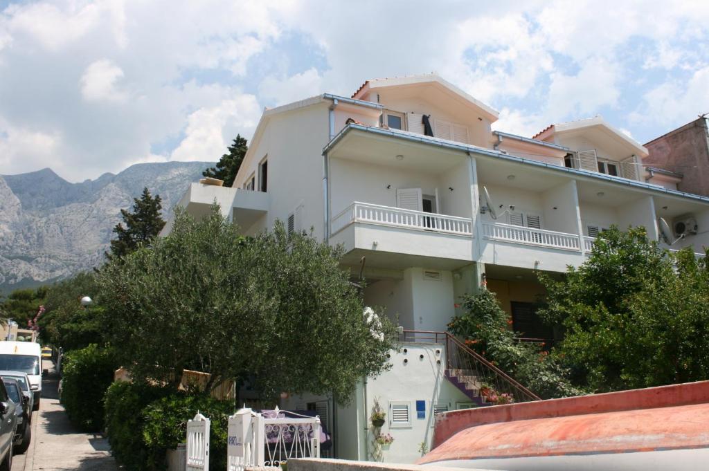 a white building with a balcony on a street at Apartments with a parking space Makarska - 6636 in Makarska