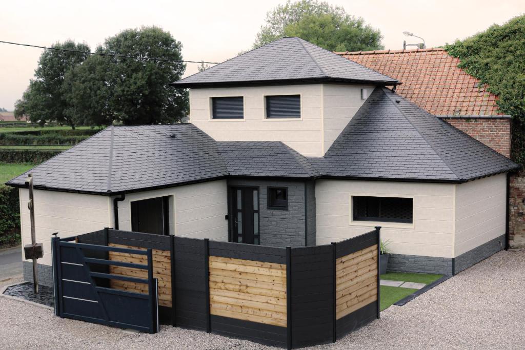 une maison avec une clôture noire devant elle dans l'établissement Le gîte suspendu, jeux d'énigmes et chambre cachée, à Saint-Blimont