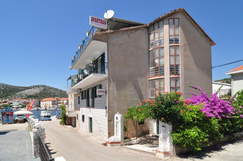 a building on the side of a street with flowers at Apartments by the sea Seget Vranjica, Trogir - 6597 in Seget Vranjica
