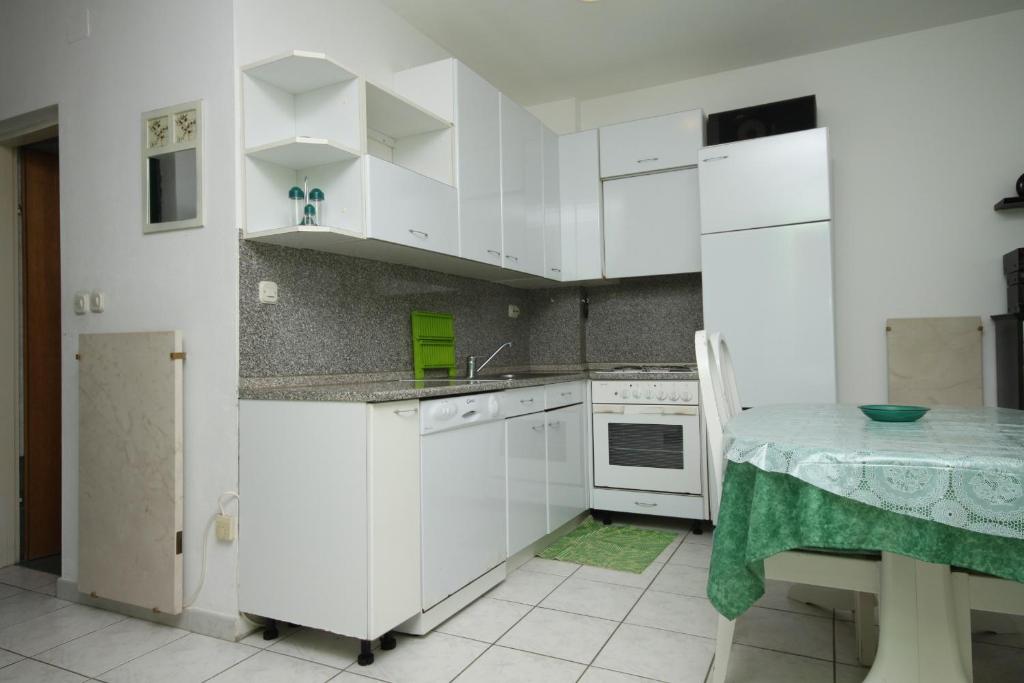 kuchnia z białymi szafkami i stołem w obiekcie Apartments by the sea Povljana, Pag - 6502 w mieście Povljana