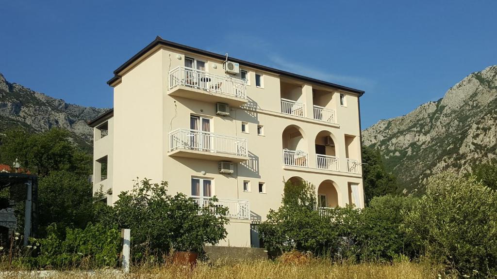 a large white building with balconies on a mountain at Apartments with a parking space Gradac, Makarska - 6724 in Gradac