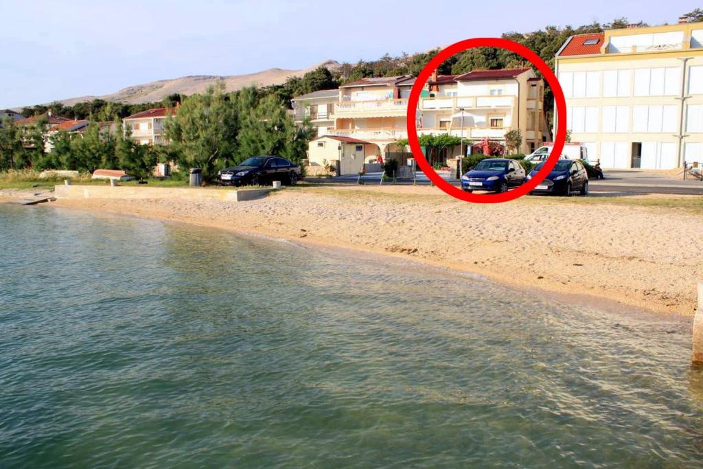 czerwony krąg na plaży obok wody w obiekcie Apartments by the sea Pag - 6448 w mieście Pag