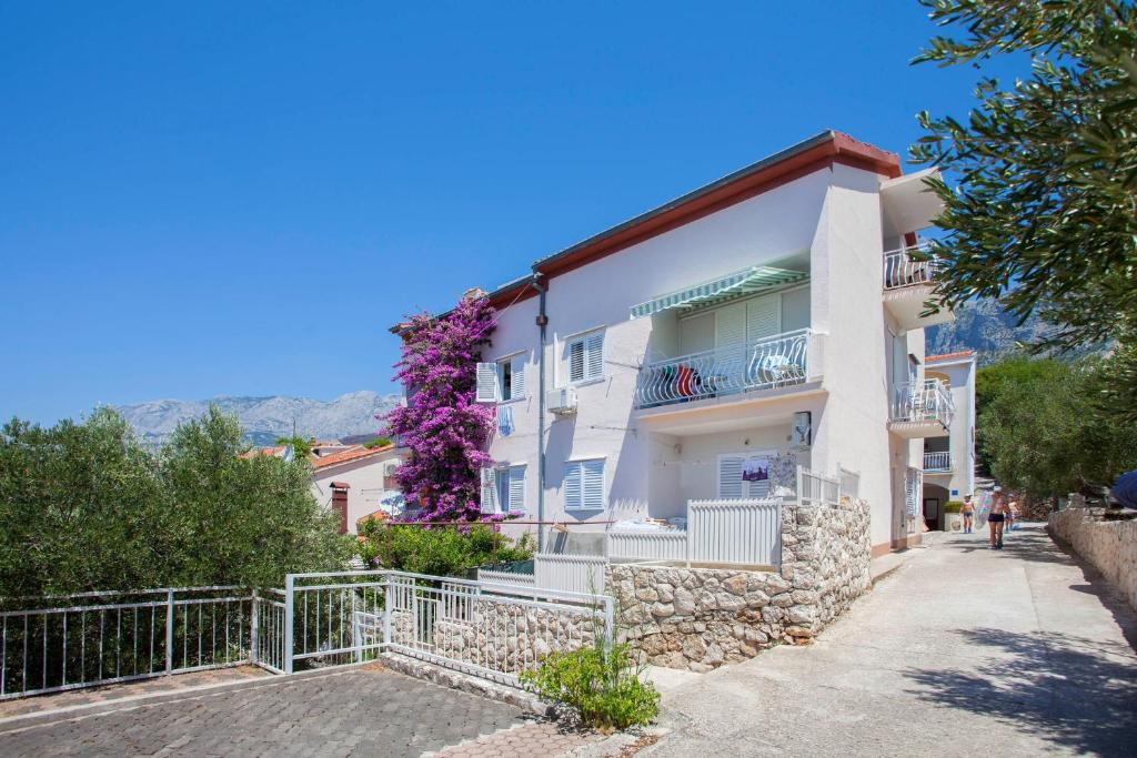 a white building with purple flowers on it at Apartments by the sea Podgora, Makarska - 6671 in Podgora