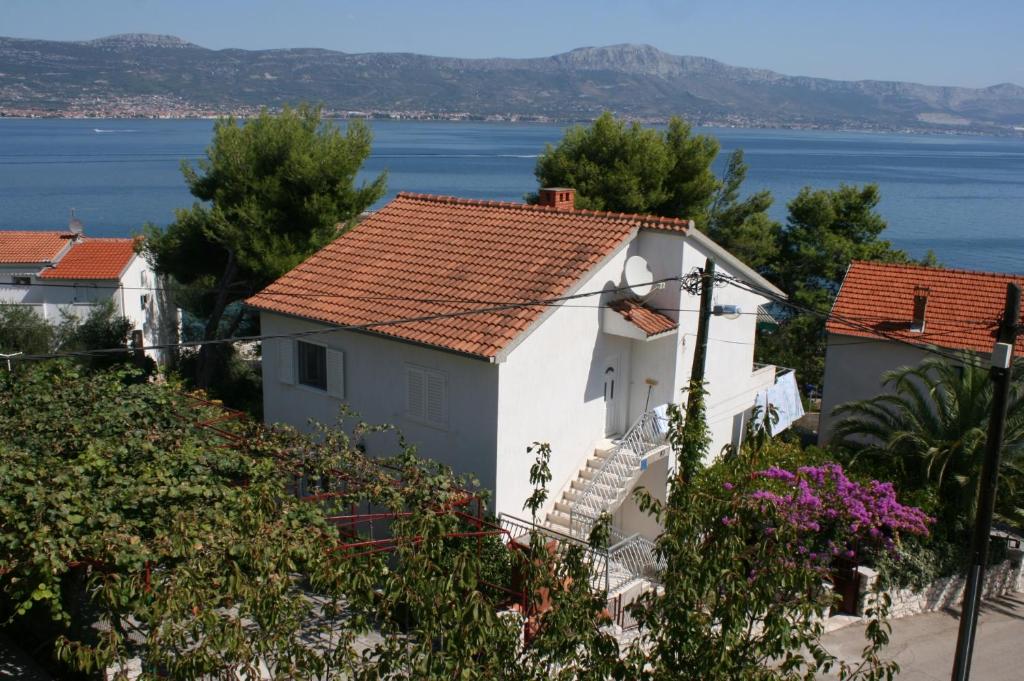 una casa blanca con una escalera junto al agua en Apartments by the sea Slatine, Ciovo - 6888 en Trogir