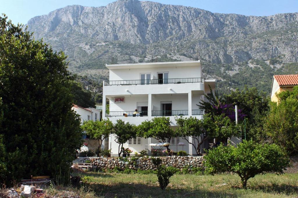 ein weißes Haus mit einem Berg im Hintergrund in der Unterkunft Apartments by the sea Drvenik Donja vala, Makarska - 6701 in Drvenik