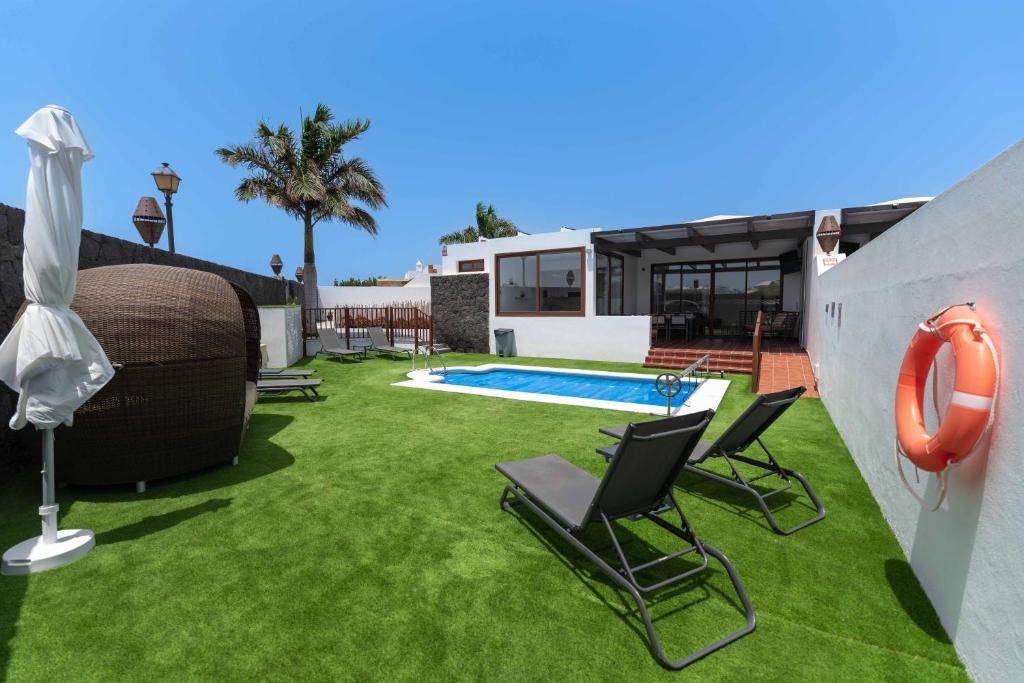 un patio con sillas y una piscina en Villa Sea Breeze Jarea, en Playa Blanca