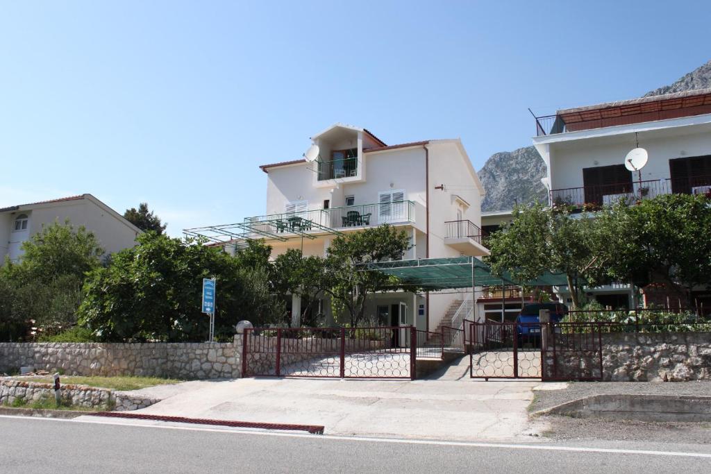 un edificio con una valla frente a una calle en Apartments and rooms with parking space Gradac, Makarska - 6819, en Gradac