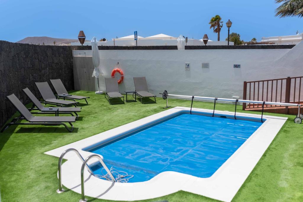uma piscina num relvado com espreguiçadeiras e uma piscina em Villa Sea Breeze Callao em Playa Blanca