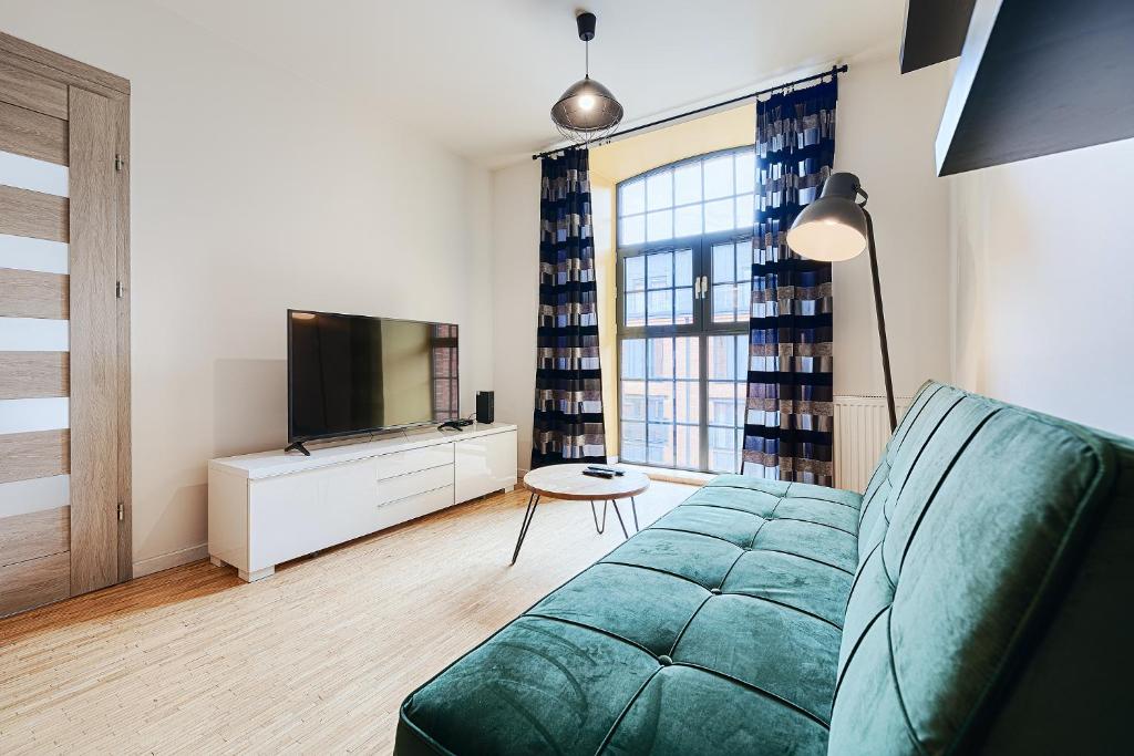 a living room with a couch and a television at Loft Green by LookAp in Łódź