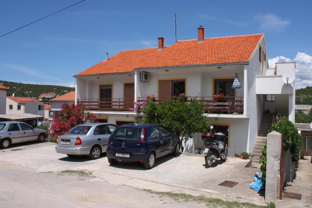 een huis met auto's geparkeerd op een parkeerplaats bij Apartments by the sea Tisno, Murter - 5091 in Tisno