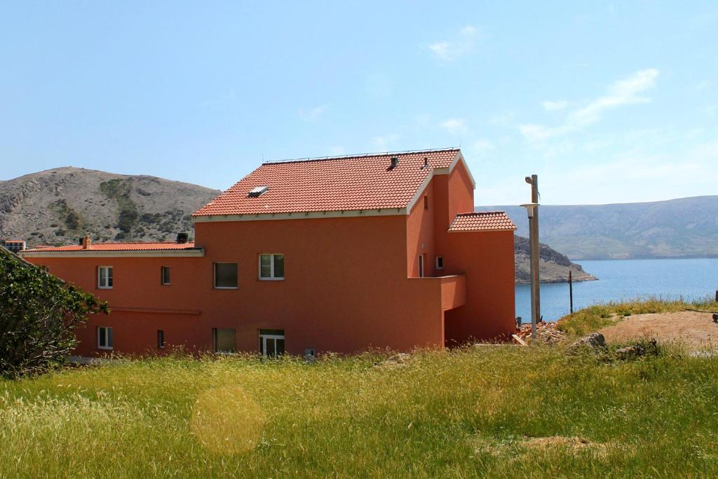 ein rotes Haus mit Blick auf das Wasser in der Unterkunft Rooms by the sea Metajna, Pag - 6487 in Metajna